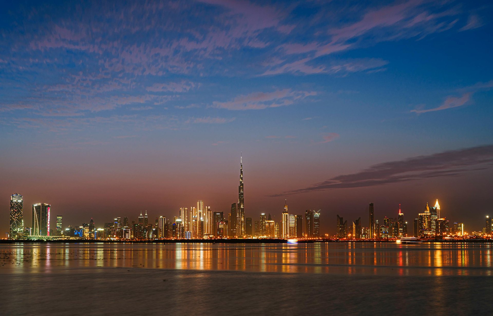 Burj Khalifa and Downtown Dubai skyline at twilight, reflected in the water